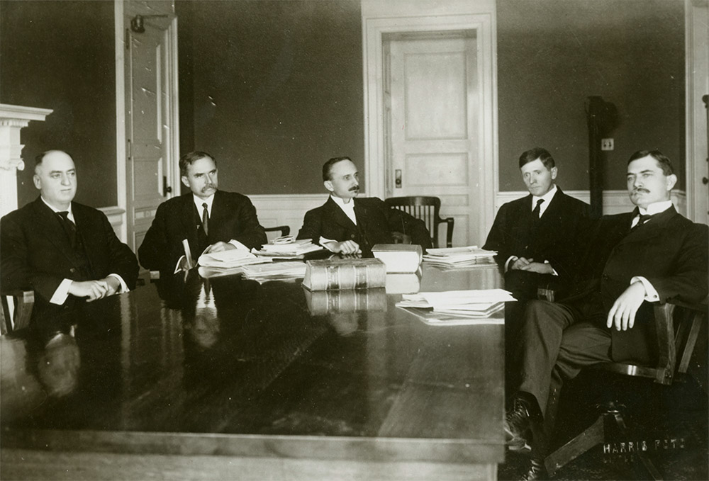 Group of white men in suits sitting at table