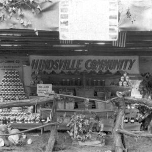 cans stacked in a pyramid and other cans and jars on display under a sign saying "Hindsville Community"