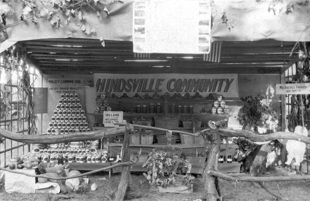 cans stacked in a pyramid and other cans and jars on display under a sign saying "Hindsville Community"
