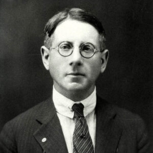 White man in suit and tie and round glasses