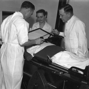 White medical professionals in white jackets attending to patient using machine