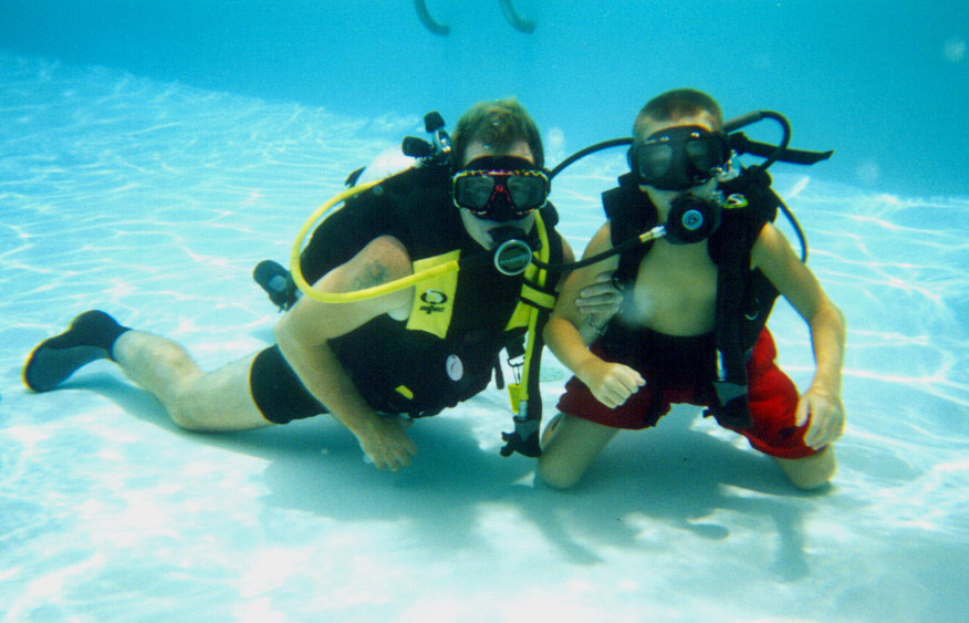 One white adult and one child under water with scuba gear