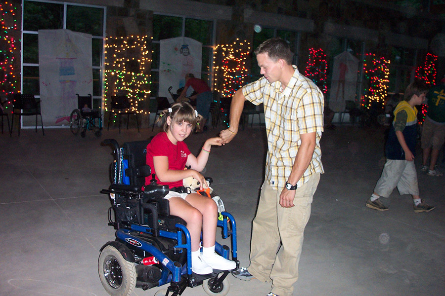 White girl in wheelchair dancing with white man standing