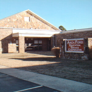 Stone and brick building with metal roof and stand-alone sign "Arch Ford Education Service Cooperative"