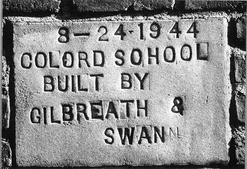 Concrete plaque embedded in brick building reading "Colored School Built by Gilbreath and Swan."