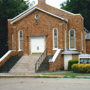 Multistory tan brick church building with stairs leading up to entrance