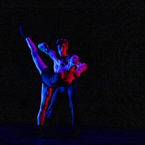 Man and woman dancing together on stage with multi-colored lights