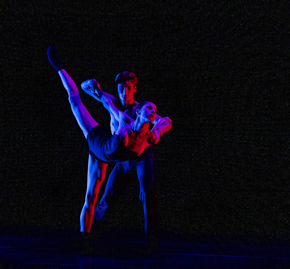 Man and woman dancing together on stage with multi-colored lights