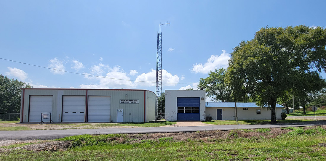 metal building with bays and low white building with a blue bay with tall antenna behind them