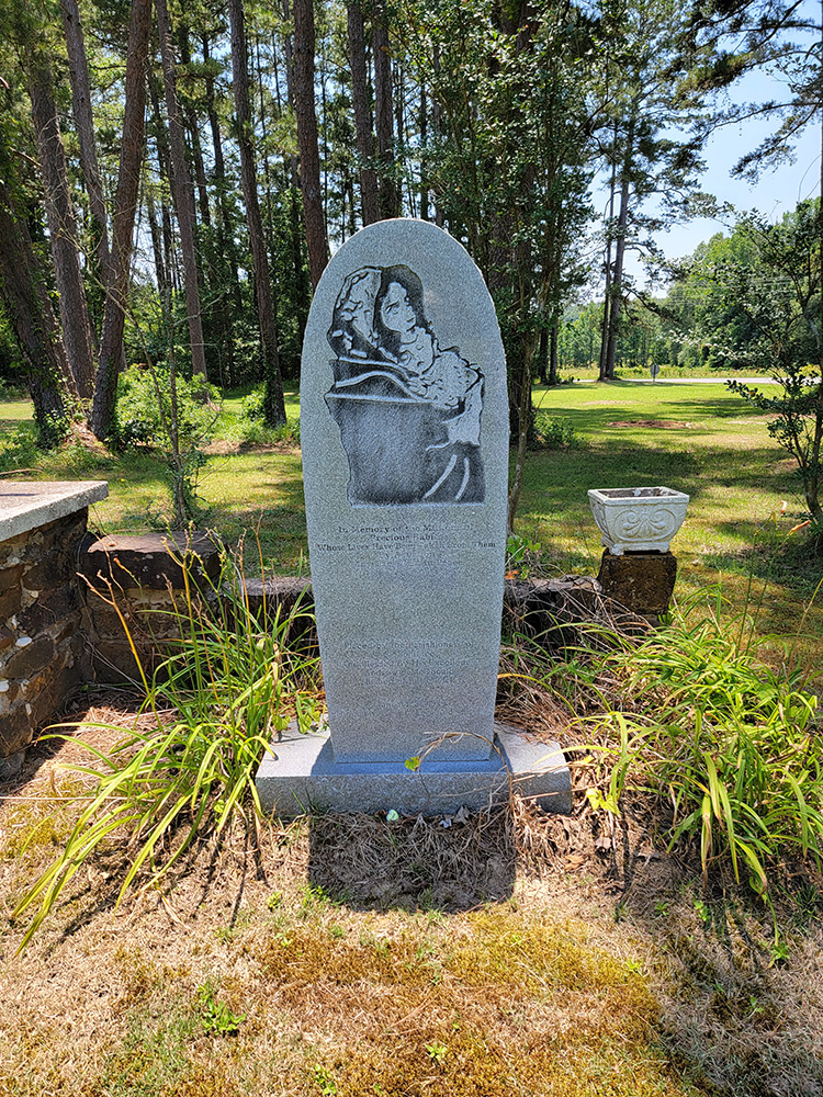 Stone memorial with words and picture of mother and child carved into it