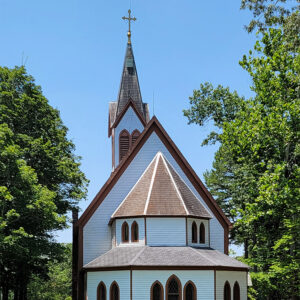 Multistory wooden white church building with brown roof and steeple with cross on top