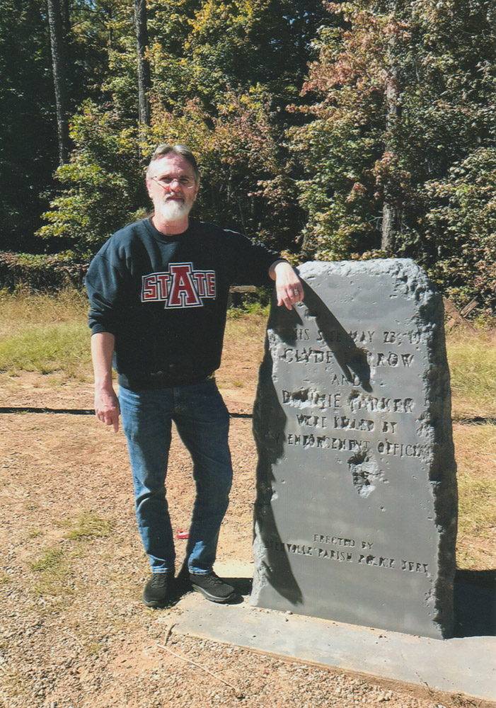 Man with beard standing next to engraved stone