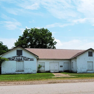 Single story white brick building with shuttered windows and sign saying "American Legion Post 222"