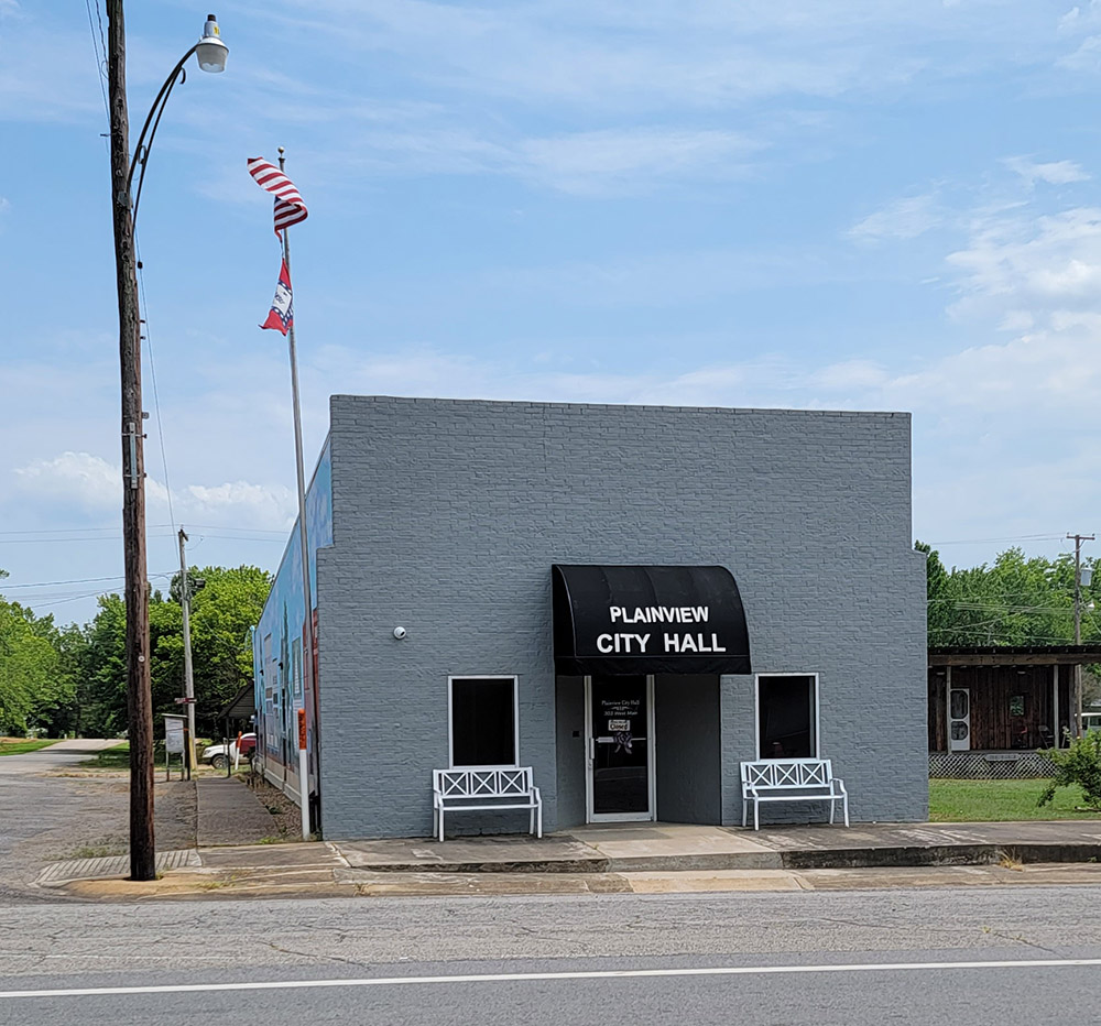 Multistory gray brick building with awning saying "Plainview City Hall"