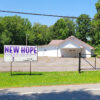 Single story church building with large parking lot and sign saying "New Hope"