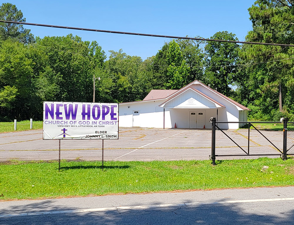 Single story church building with large parking lot and sign saying "New Hope"