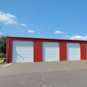 Red metal building with four white bay doors