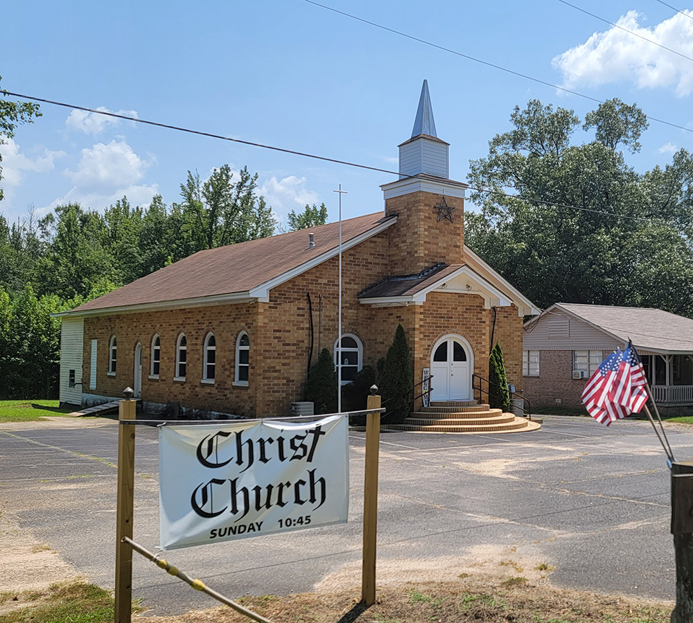 Tan brick church building with short white steeple