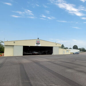 Metal building with planes inside next to expanse of concrete