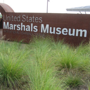 Brown metal sign with sheriff's star and "United States Marshals Museum and National Learning Center"
