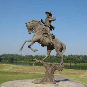 Statue of man riding horse while dressed in cowboy garb