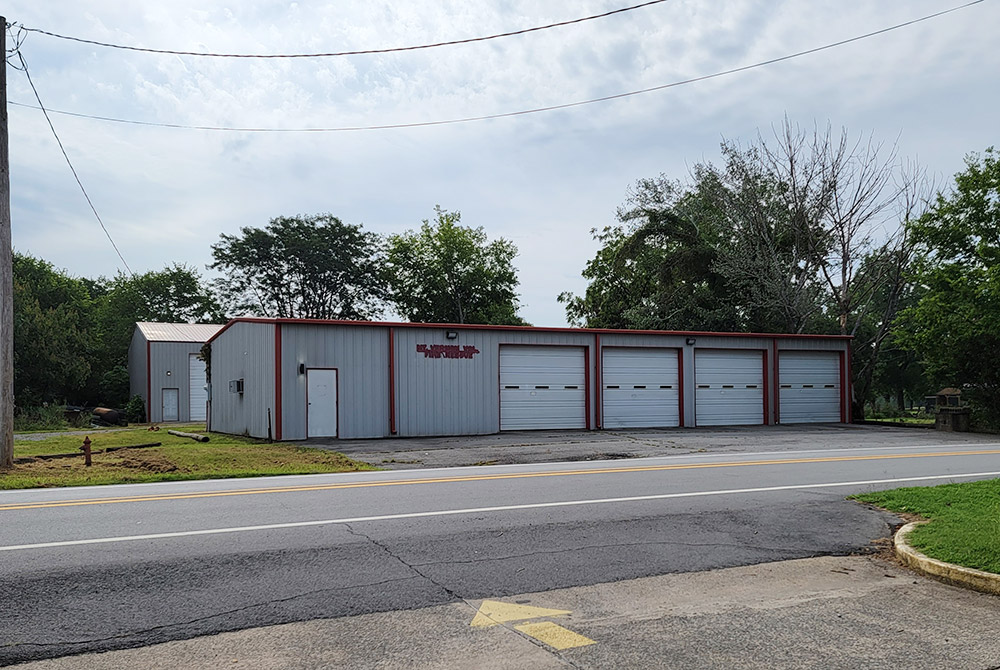 gray metal building with four garage doors and one entrance door by road