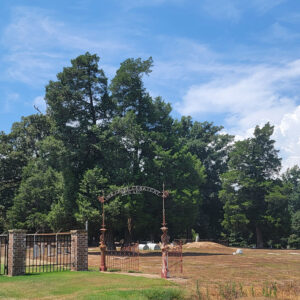 Cemetery with trees and gravestones and a fence with brick columns