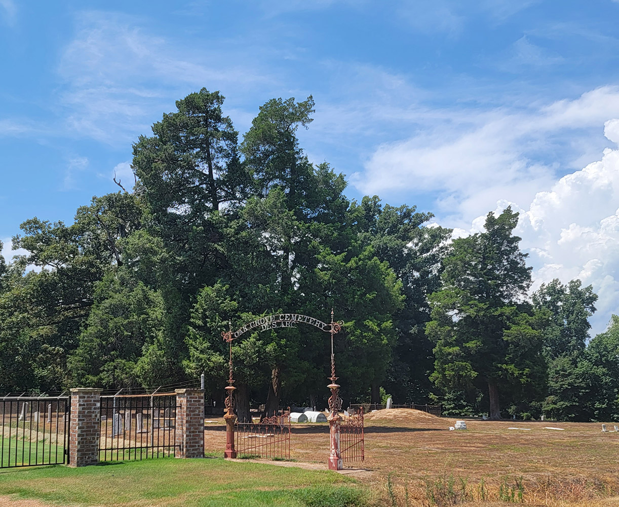 Cemetery with trees and gravestones and a fence with brick columns