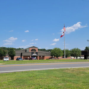Single-story red brick building with a flagpole with Arkansas and American flags