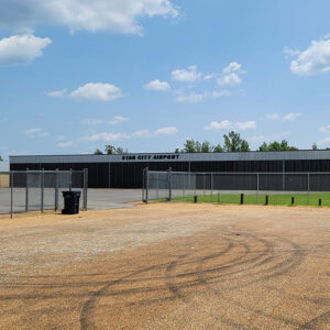 Single-story metal brick building with a chain-link fence in front