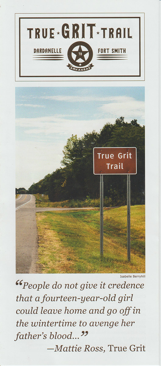 Paper flyer advertising "True Grit Trail" with photograph depicting roadside and sign