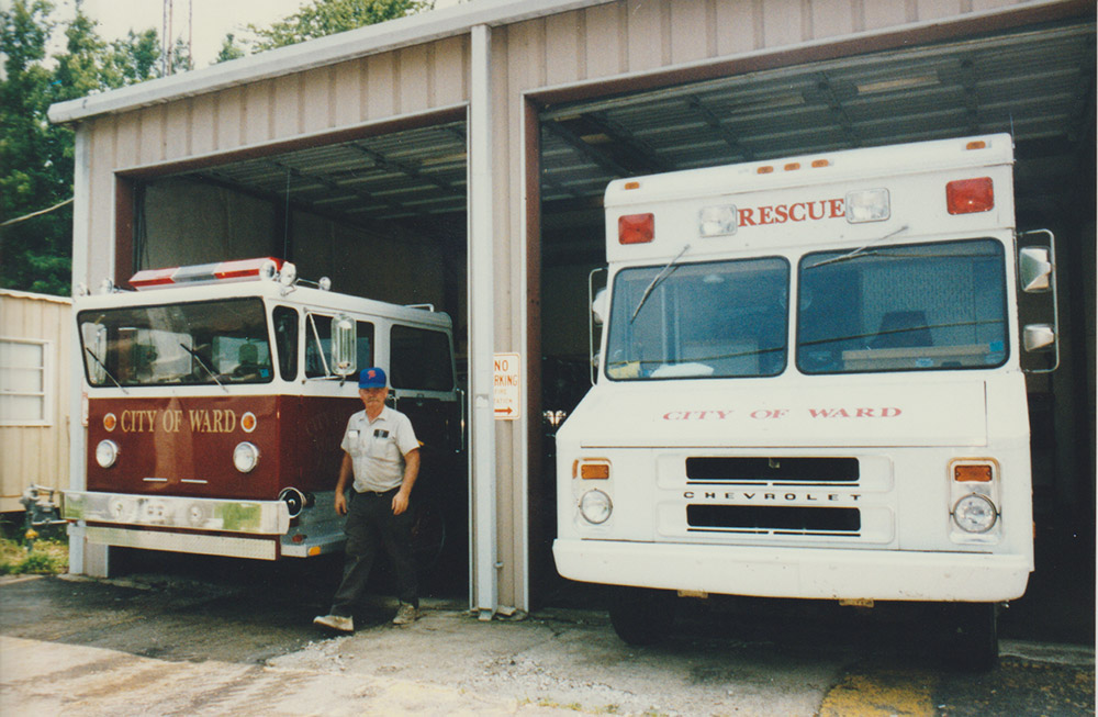 Fire truck and ambulance both printed with "City of Ward" with a man standing by the fire truck