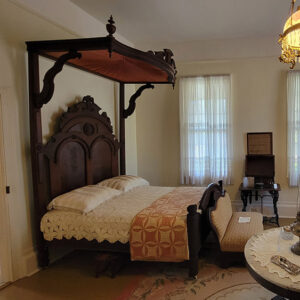 Wallpapered room with antique canopy bed and other wood furniture