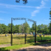 Cemetery with graves behind fence with arched entrance saying "Buena Vista Cemetery"