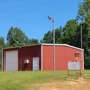 Single story red metal building with one regular door and one bay door