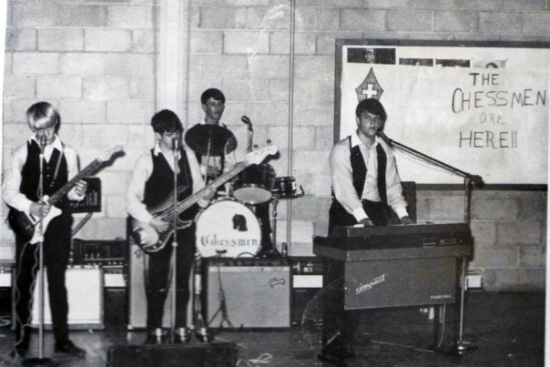 Group of young white men playing instruments dressed alike in white shirts and dark pants and vests
