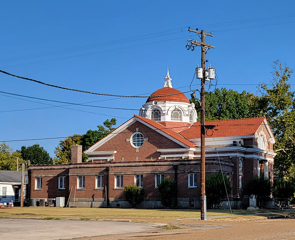 Multistory red brick church building with ornate dome with windows around it