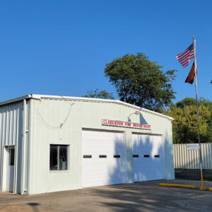 white metal building with two bay doors and a sign saying "Clarendon Fire Department"