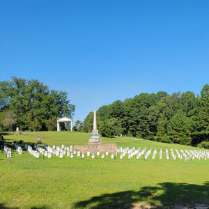 Cemetery with straight rows of small white tombstones and a large monument in the middle