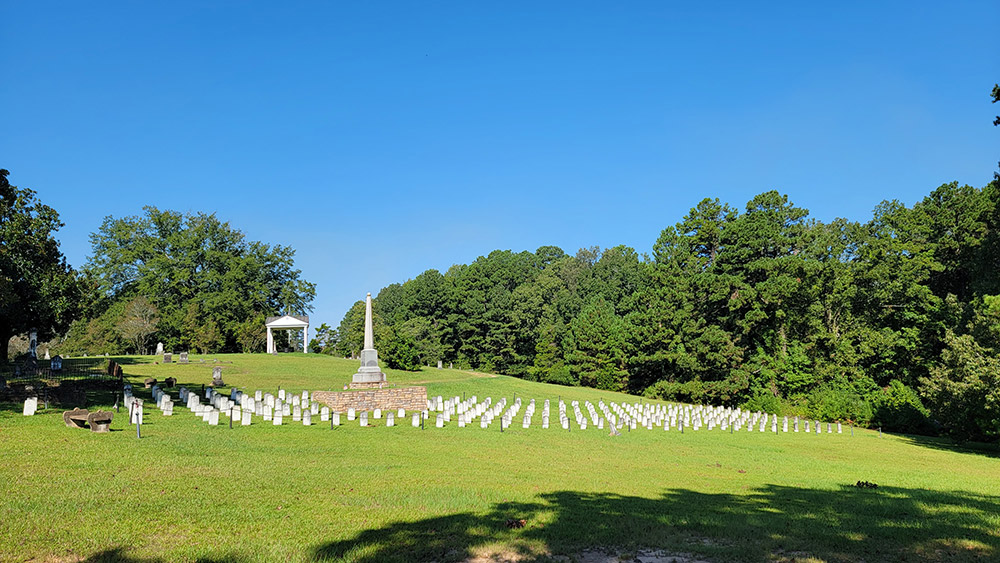 Cemetery with straight rows of small white tombstones and a large monument in the middle