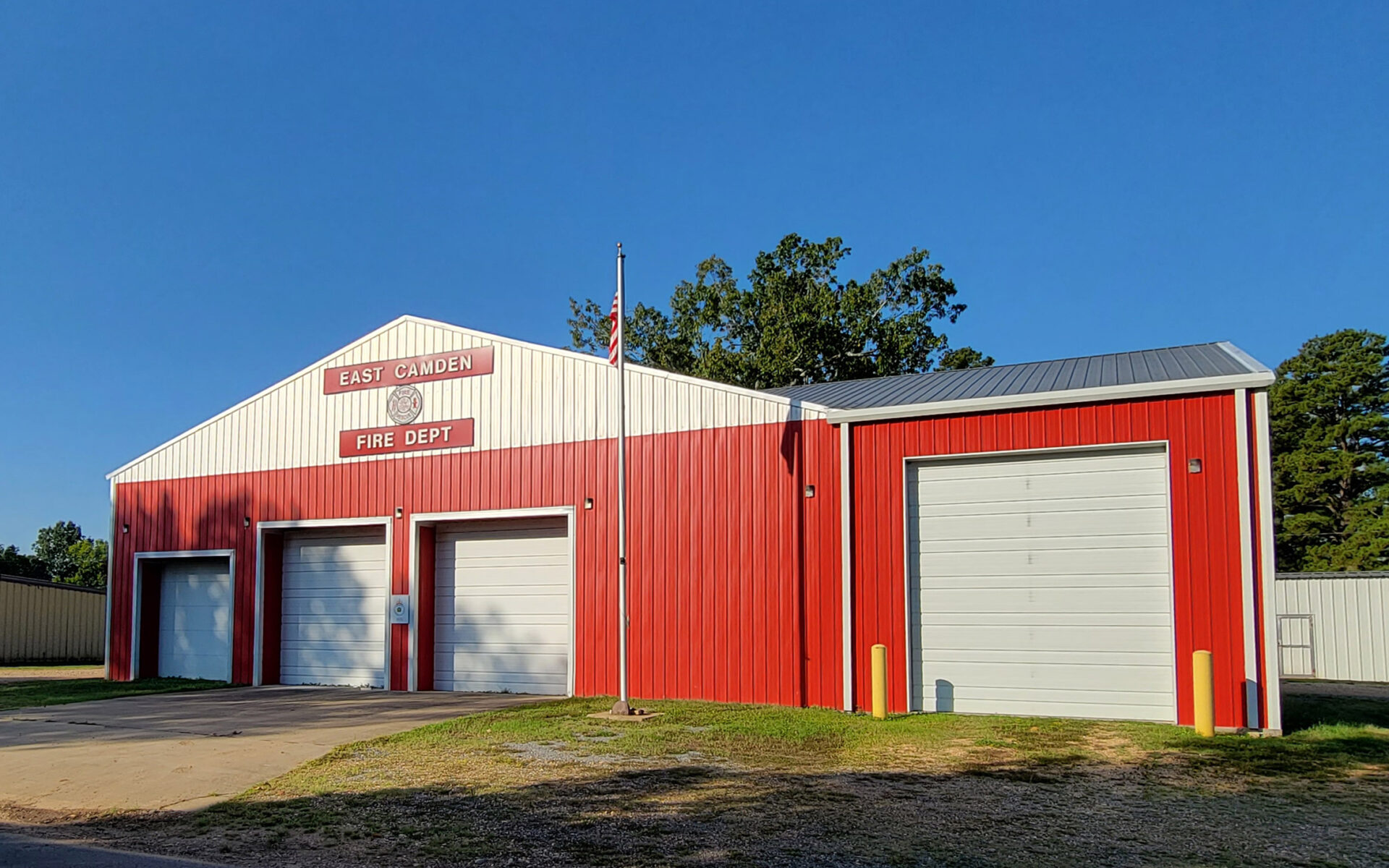Red and white metal building with four bay doors