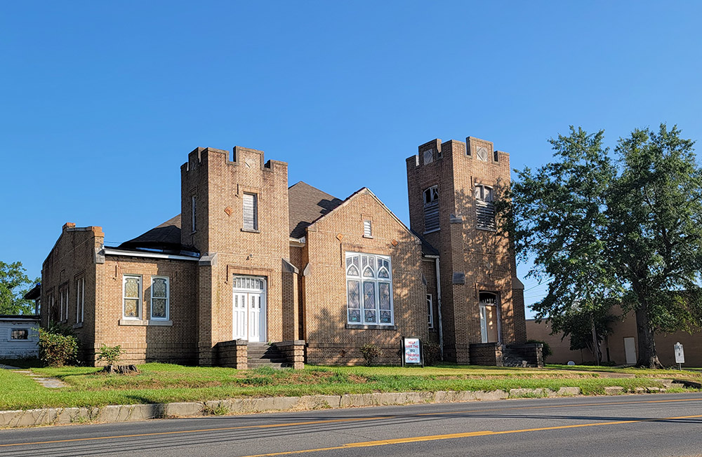 Multistory tan brick church building with two towers of differing heights