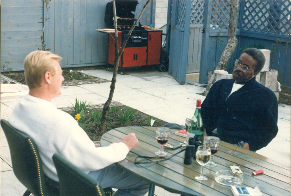 African American man with glasses sitting at picnic table with white man