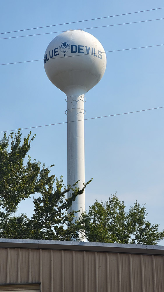 tall white water tower saying "Blue Devils" with devil head