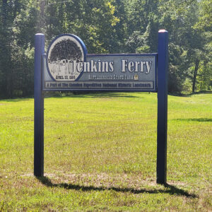 Wooden sign "Jenkins Ferry Battleground State Park" with trees in background