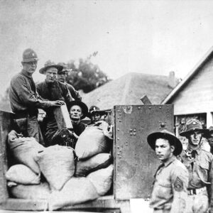 White men in military garb sitting in and standing around a truck loaded with bags