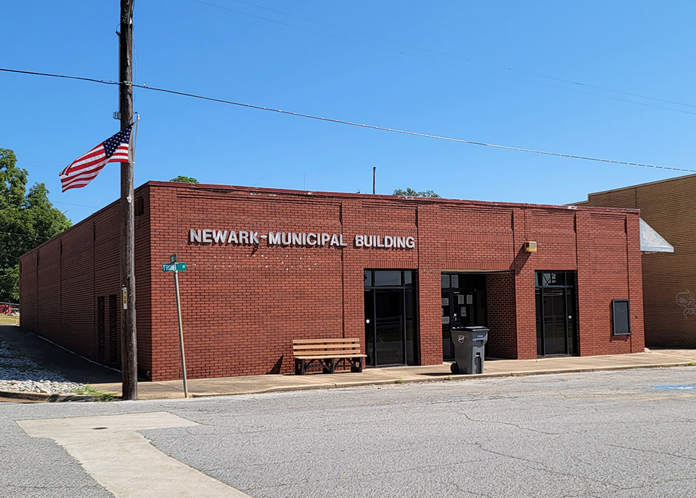 Single story red brick building with lettering saying "Newark Municipal Building" on street corner