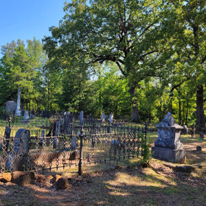 Cemetery with graves and trees and wrought iron fencing