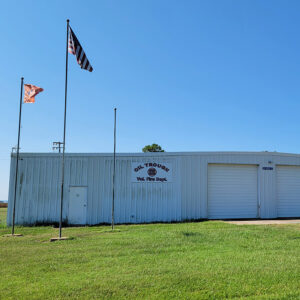 White metal fire department building with two garage bay doors and flags on flagpoles