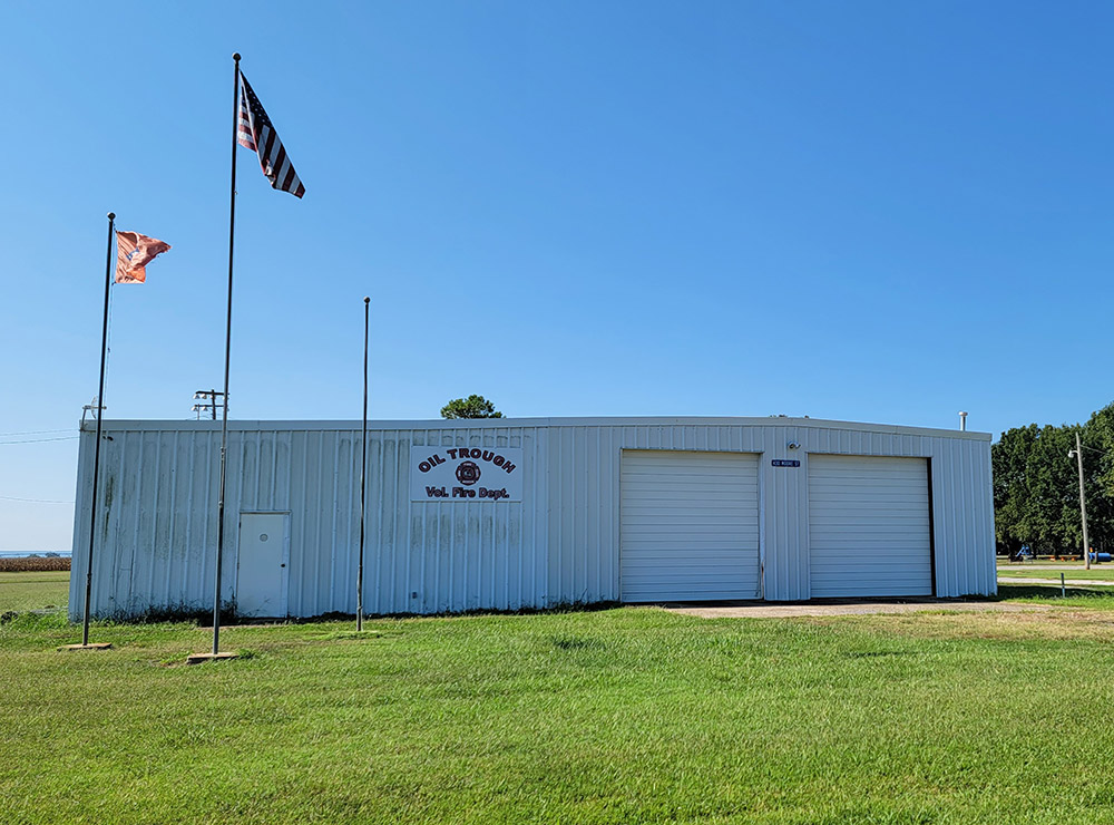 White metal fire department building with two garage bay doors and flags on flagpoles